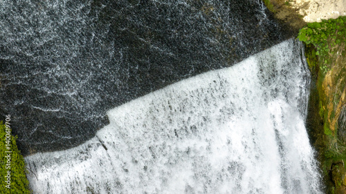 Obraz na płótnie Aerial closeup of a small waterfall flowing into a pond. w salonie