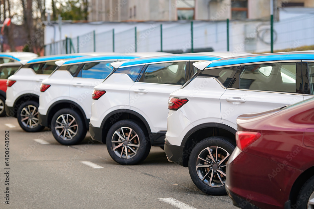 New SUV cars fleet stock at parking lot. Automobile market production, outdoor warehouse. Row of modern white and red cars parked in an urban parking lot. Stocks of new modern cars, rear view