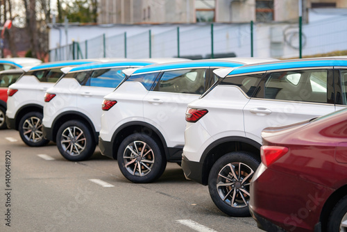 Obraz na płótnie New SUV cars fleet stock at parking lot. Automobile market production, outdoor warehouse. Row of modern white and red cars parked in an urban parking lot. Stocks of new modern cars, rear view w salonie