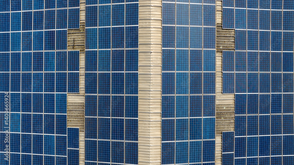 Aerial perpendicular view of solar panels on the roof of an industrial building.