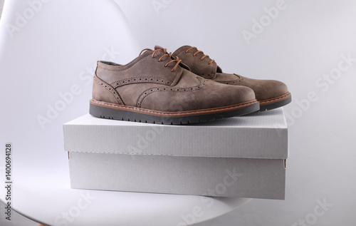 Cardboard shoe box with brogue boots on table