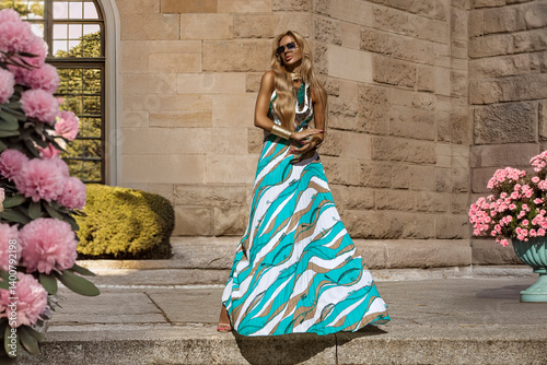 Elegant Woman in Flowing Colorful Maxi Dress Posing in the City in Summer Sunlight