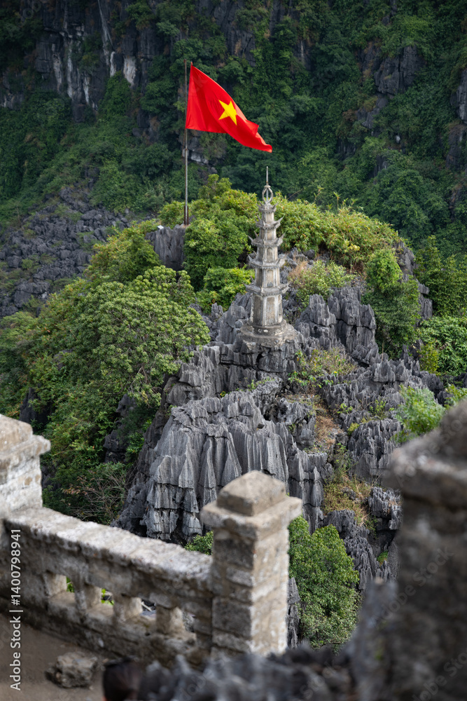 Stunning view from the Hang Múa Viewpoint with a pagoda and the Vietnamese national flag in the distance. Ninh Binh, Vietnam.