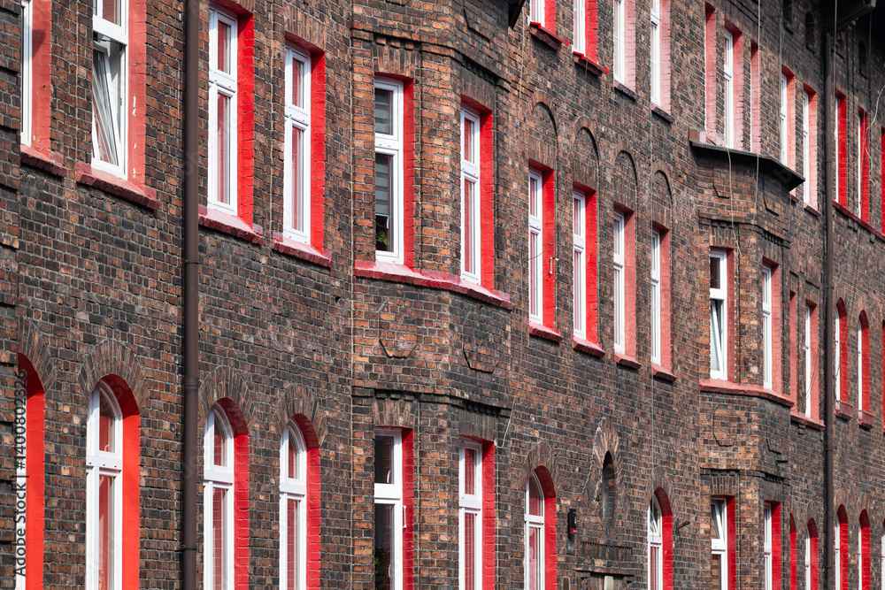 Red brick tenement house elevation. Red window frames. Old workers' housing estate. Unique architecture. Katowice Nikiszowiec. Poland