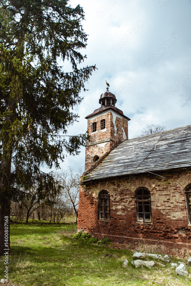 Old brick church with a bell tower surrounded by trees on a cloudy day. Ukraine. Old brick church with a bell tower surrounded by trees on a cloudy day. Ukraine.