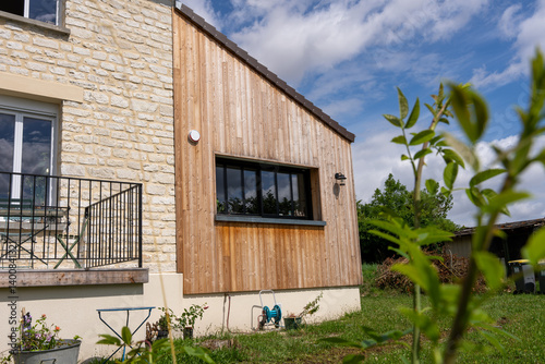 Extension moderne d’une maison avec bardage en bois, contrastant harmonieusement avec la structure ancienne en pierre.