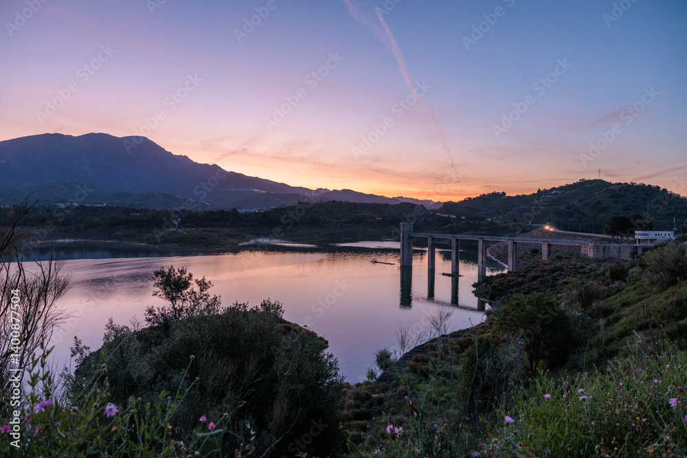 Guadalhorce reservoir reflecting vibrant sunset over mountains in malaga, spain