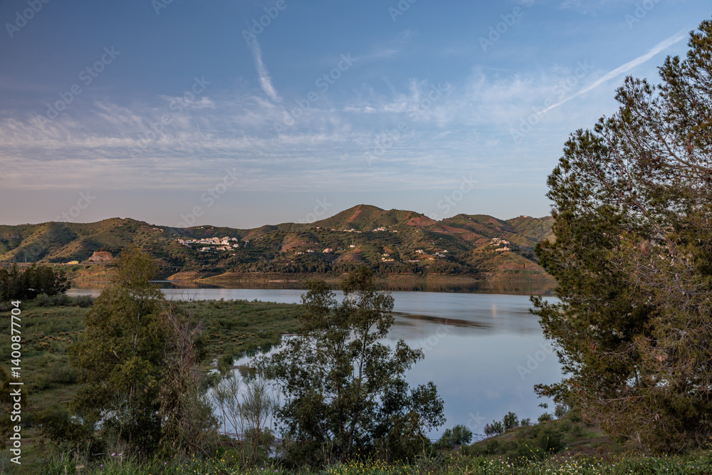 Guadalhorce reservoir reflecting the hills and cloudy sky at sunset in malaga, spain