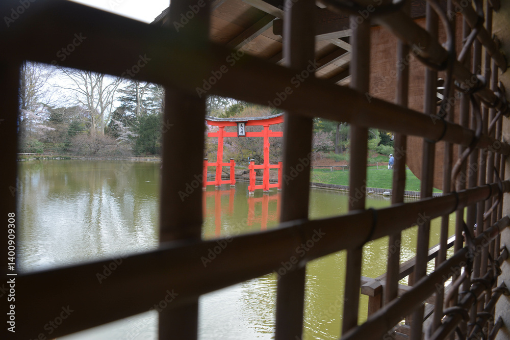 Obraz premium A peaceful park by a calm lake, lined with striking wooden monuments. Surrounded by greenery, the scene reects tranquility and natural beauty in perfect harmony