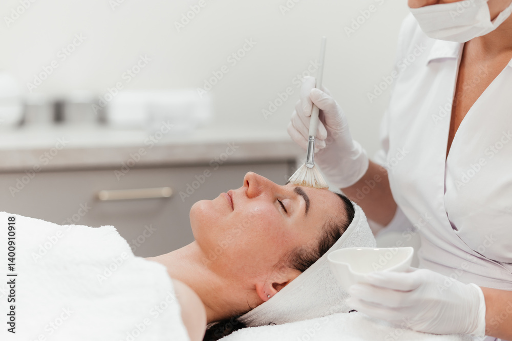 Naklejka premium Cosmetology beauty procedures. Lady receiving rejuvenation anti aging treatment, facial chemical peel therapy in beauty salon or medical center. Wellness. Mask with retinol. Free copy space