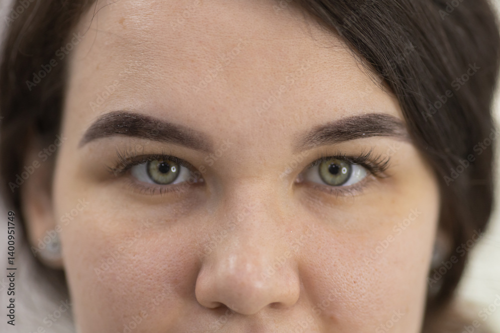 Fototapeta premium woman with green eyes and a dark eyebrow. The woman has a light brown eyebrow