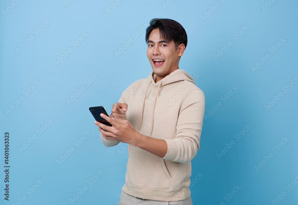 Happy smiling young asian man using mobile phone isolated on blue background. teen social media communication online. Happy smiling young asian man using mobile phone isolated on blue background. teen social media communication online.