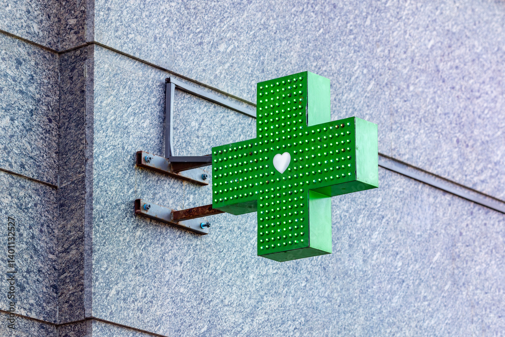 Closeup of a green pharmacy sign symbol outside a pharmacy store building