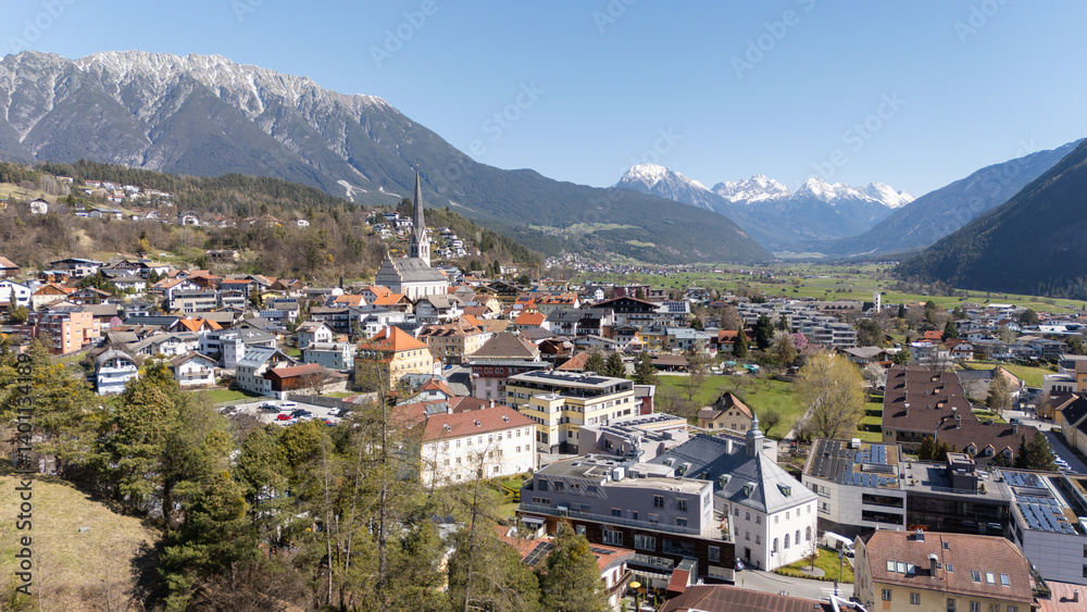 Obraz premium Aerial winter view of the city centre of Imst in Tirol. Beautiful city view with Rauchberg and Heiterwand mountain in the background and Pfarrkirche Imst. Tourist travel destination in Tyrol, Austria.
