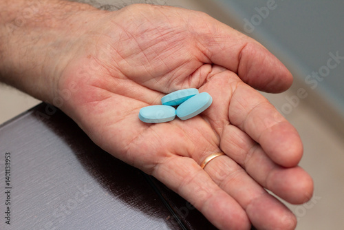 Mão de um homem idoso com alguns comprimidos de viagra.