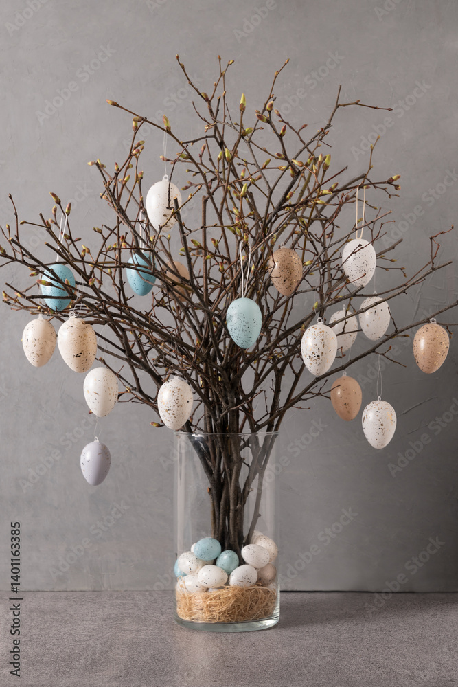 Easter tree decorated colorful pastel white and beige eggs. Birch branches with hang eggs in glass vase on gray background. DIY. Vertical format. Creative Easter greeting card.