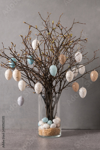 Obraz na płótnie Easter tree decorated colorful pastel white and beige eggs. Birch branches with hang eggs in glass vase on gray background. DIY. Vertical format. Creative Easter greeting card. w salonie