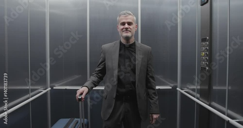 Happy priest going on a journey, he is taking the elevator and carrying luggage