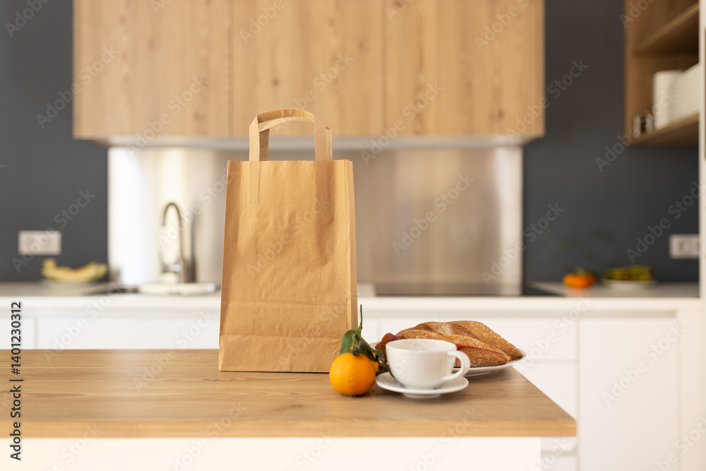 Paper shopping bag and fresh citrus, cup of coffee and sandwich on countertop in kitchen. Space for text. Delivery concept, mock up