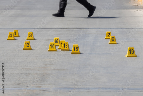Law enforcement officer walking through a crime scene surrounded by evidence markers.