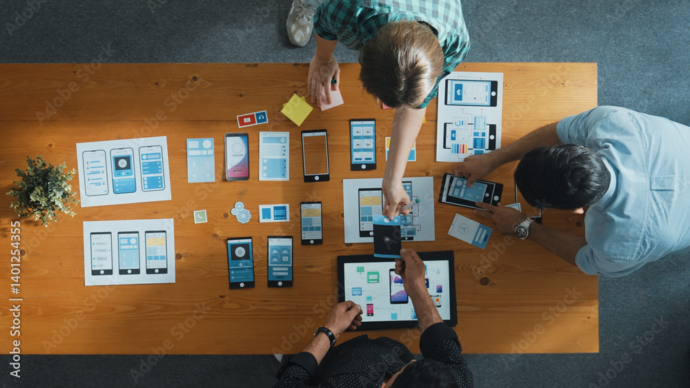 Top view of smart Ui designer brainstorming and planning about Ux Uo design or mobile interface wireframe design with diverse develop team. Caucasian programer walking and joining meeting.Convocation.