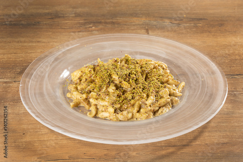 trofie pasta with pistachios on a transparent glass plate, wooden table background