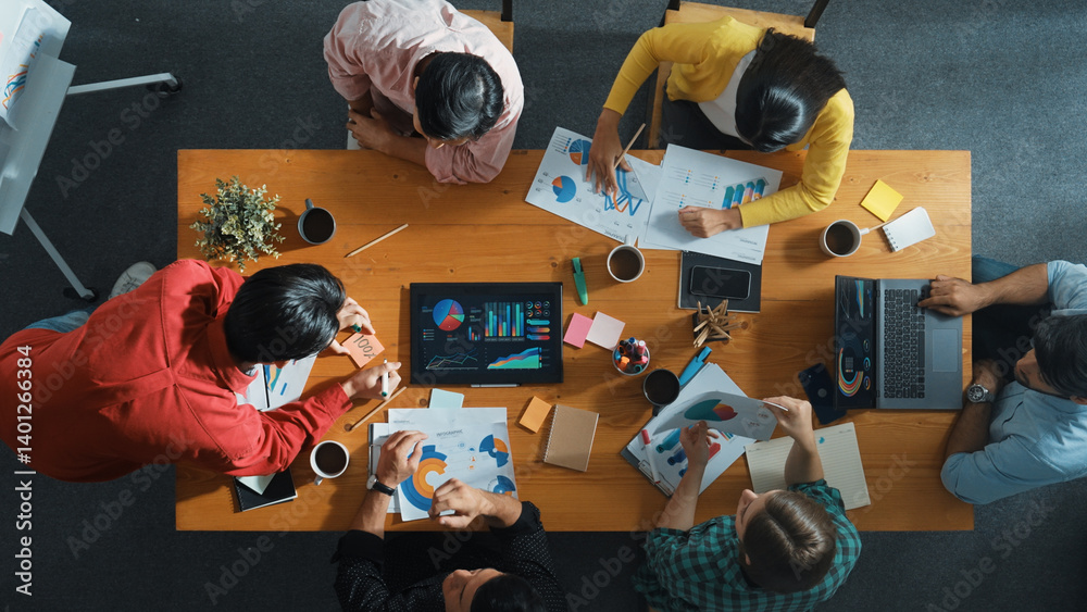 Top down view of investor brainstorming while looking at financial statistic document. Group of diverse people sharing marketing idea or planning marketing campaign with skilled leader. Convocation.