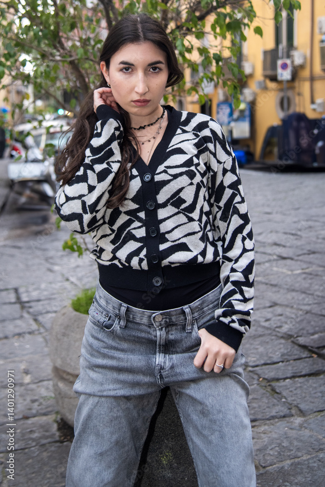 Fototapeta premium Fashion model posing in urban setting, wearing stylish cardigan and jeans