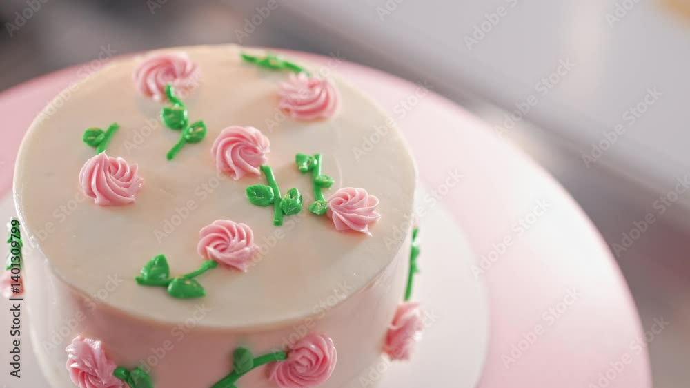 Elegant rotating cake,pink buttercream flowers on white frosting. Bakery, pastry Elegant rotating cake,pink buttercream flowers on white frosting. Bakery, pastry