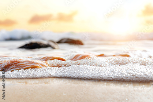 serene beach scene featuring gentle waves lapping over smooth stones at sunset, creating tranquil atmosphere