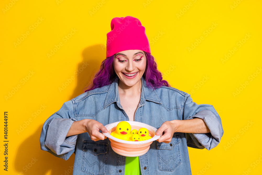 Happy Young Woman Holding Rubber Ducks Against a Vibrant Yellow Background Wearing a Pink Hat and Denim Jacket Happy Young Woman Holding Rubber Ducks Against a Vibrant Yellow Background Wearing a Pink Hat and Denim Jacket