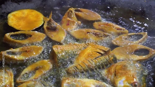 Hilsha fish is fried in a big pan along with shrimp and eggplant, Hilsha Fish and shrimp Simmering in mustard oil, traditional Bengali style fried hilsa and eggplant	