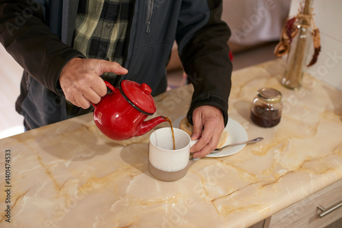 Farmer pouring steaming tea from crimson teapot into ceramic mug, homemade pastry and jam nearby, warm morning light illuminating rustic kitchen counter