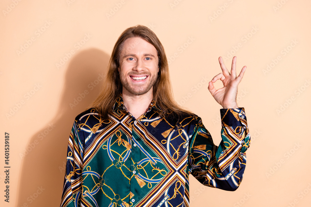 Stylish young man in a fashionable print shirt smiling confidently against a beige background Stylish young man in a fashionable print shirt smiling confidently against a beige background