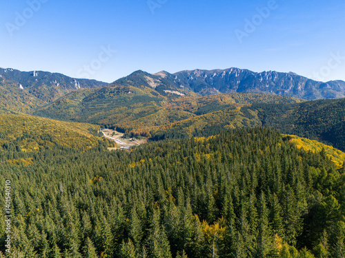 Scenic panorama of peaceful countryside in Romania with green hills, mountains, and autumn forest.