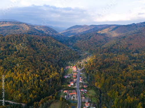 Scenic panorama of peaceful countryside in Romania with green hills, mountains, and autumn forest.