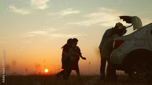 Family at sunset near car silhouettes. Parents dad mom children kids girl boy have good time together in nature family road trip by car automobile. Laughter joy delight fun freedom carefree childhood.