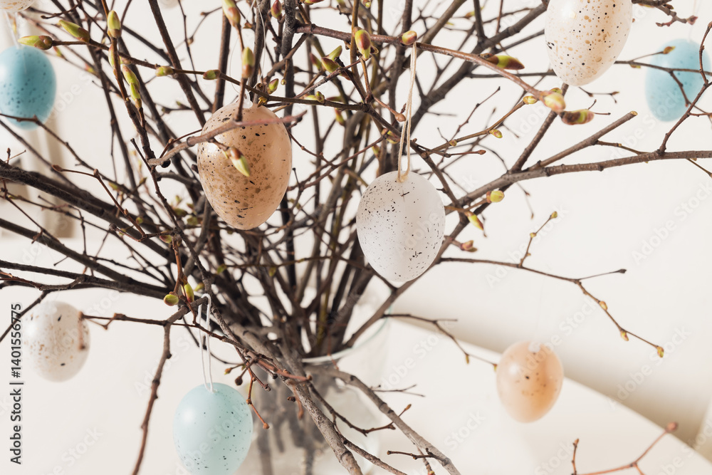 Easter tree decorated colorful pastel white and beige eggs. Birch branches with hang eggs in vase on white table. Close up