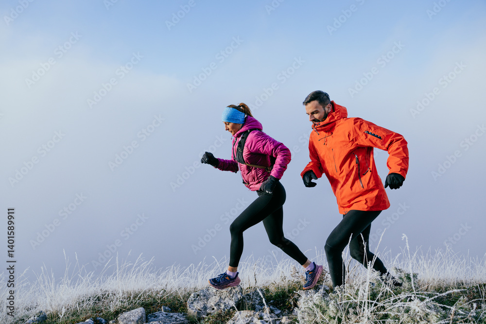 Trail running couple man and woman running on a mountain path Trail running couple man and woman running on a mountain path