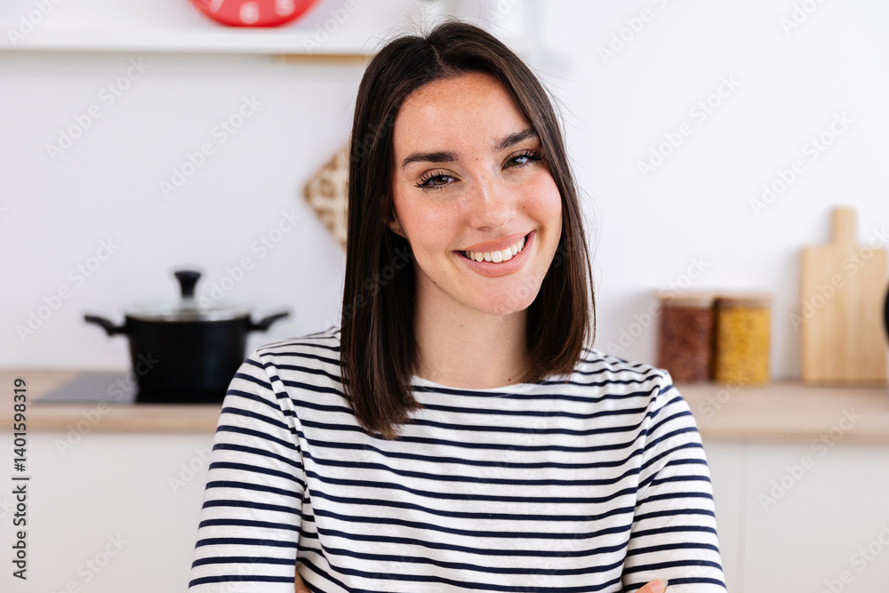 Portrait of young happy woman smile at camera sitting on table in the kitchen. POV webcam view of female student or businesswoman having a video call from home Portrait of young happy woman smile at camera sitting on table in the kitchen. POV webcam view of female student or businesswoman having a video call from home
