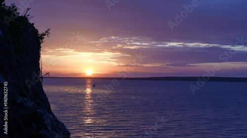 Soft Purple Sunset Over Ocean with Rock Silhouette