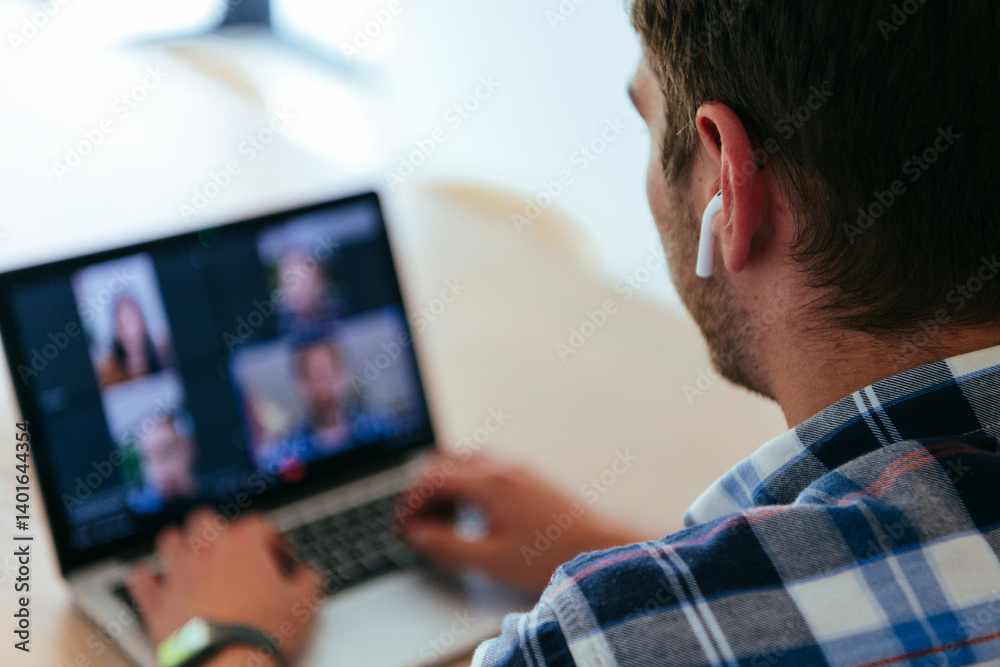 A freelancer sitting at a table in a modern living room, with headphones using a laptop for business video chat, conversation with friends and entertainment