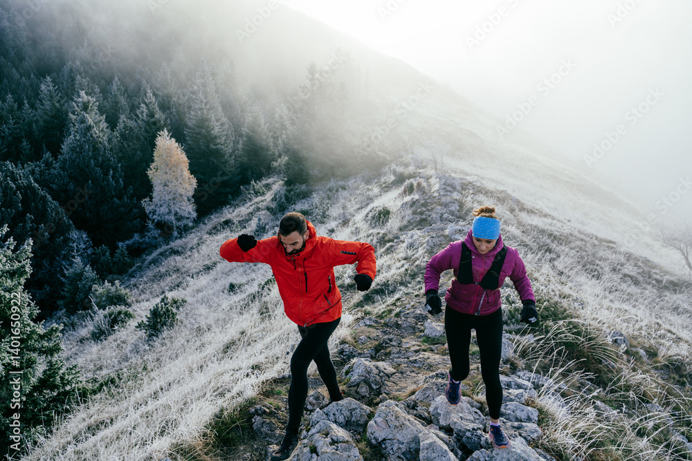 Trail running couple man and woman running on a mountain path