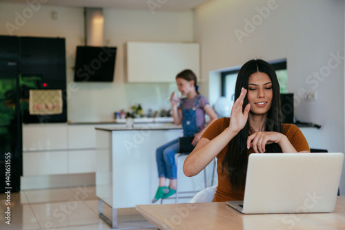 Obraz na płótnie Mother with her daughter talking on laptop with family and friends while sitting in modern living room of big house. w salonie