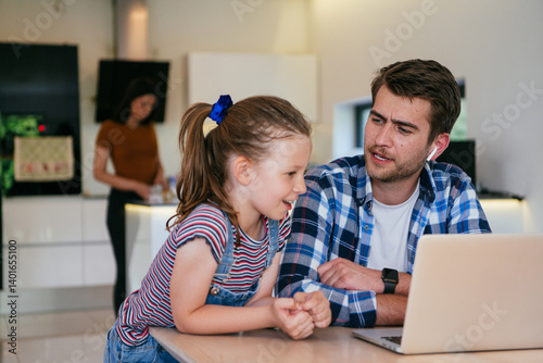 Obraz na płótnie Work from home. Daughter interrupting her father while he is having a business online conversation on his laptop while sitting in the modern living room. w salonie