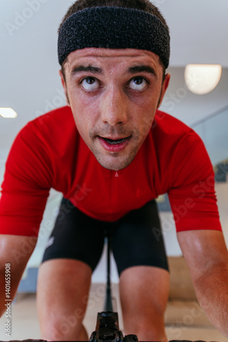 Obraz na płótnie A triathlete riding a triathlon bike on a machine simulation in a modern living room. Training during pandemic conditions. w salonie