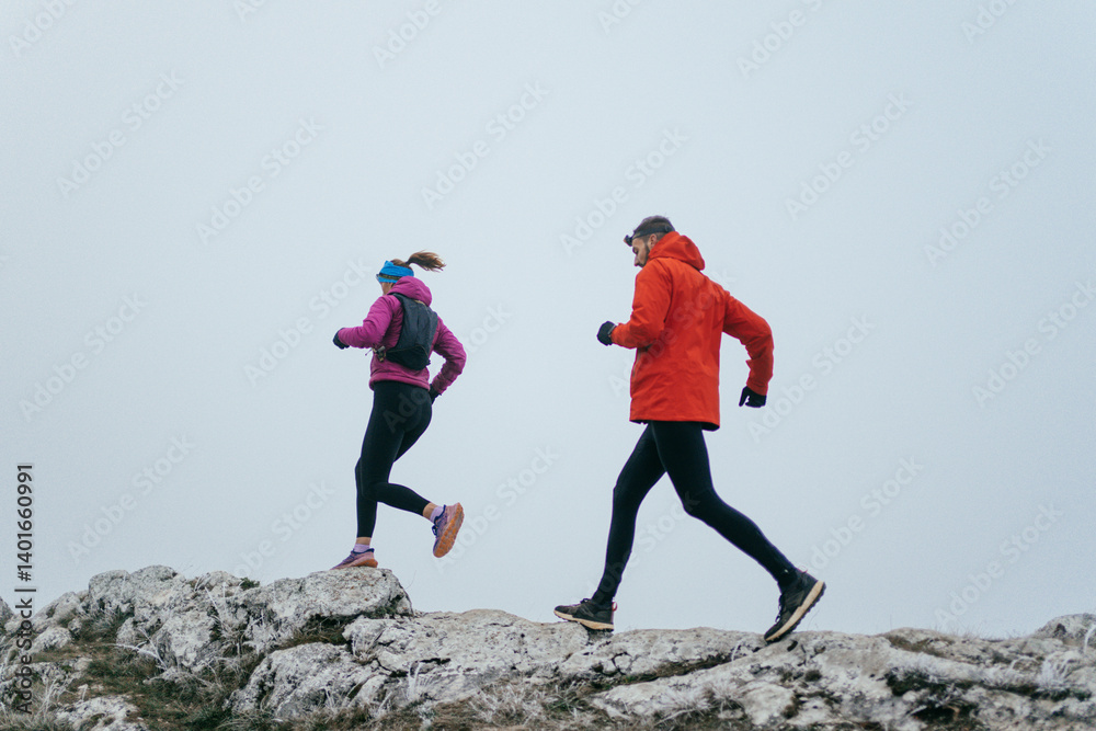 Trail running couple man and woman running on a mountain path