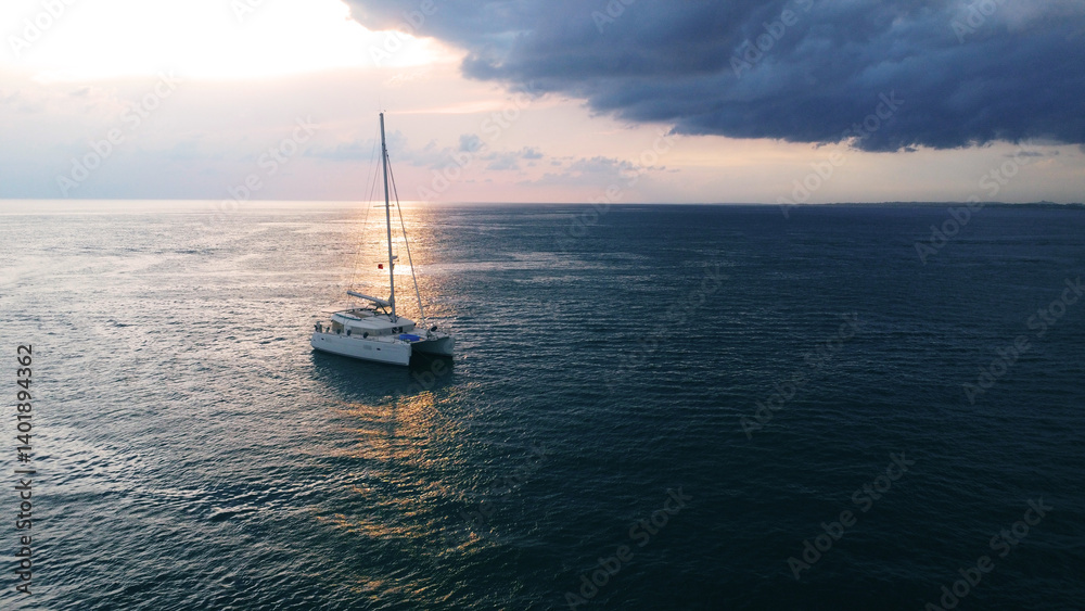 catamaran gently anchored on the calm, dark blue water at dusk