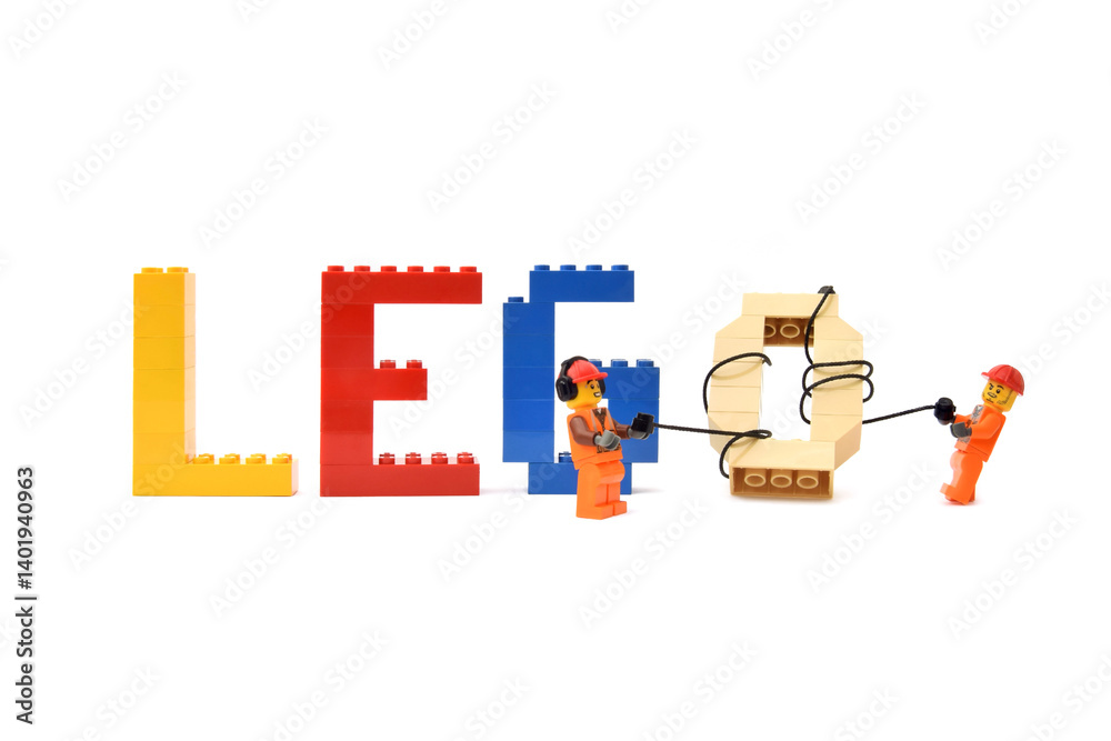 Naklejka premium Lego minifigures of workers in uniform are making a word lego from letters are made from bricks. Editorial illustrative image of popular plastic toy constructor.
