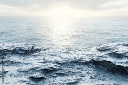 Sea view from atop rocky cliffs. The water sparkles under a cloudy sky, near the horizon